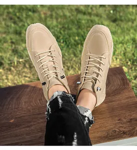 Detailopname van beige hoge herenschoenen gedragen met een zwarte distressed jeans buiten