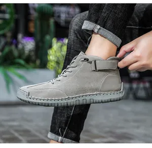 Detailed close-up of grey hand-stitched high-top Martin boots with strap for men