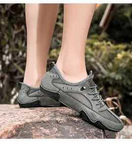 Ademende leren mesh heren sneakers in grijs, getoond op een rots buiten.
