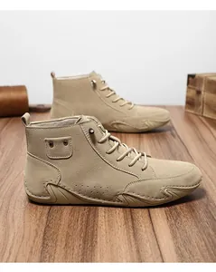 Zijaanzicht van beige suède herenboots met gedetailleerde stiksels op hout