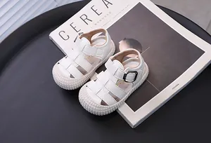 Vista superior de sandalias blancas para bebés con suela blanda sobre revista