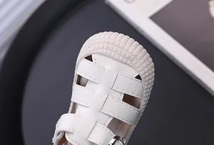 Primer plano de sandalias blancas para niños con puntera reforzada anticolisión texturizada