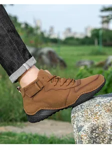 Vue lifestyle de bottines marron montantes pour hommes posées sur un rocher en plein air.