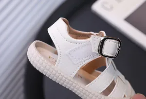 Primer plano de sandalia blanca para niño con cierre de velcro y hebilla decorativa