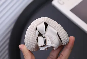 Primer plano que muestra la flexibilidad y suela blanda de las sandalias blancas para niños.