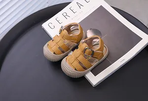 Primer plano de sandalias amarillas para bebés con punta cerrada y suela blanda.
