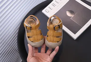 Primer plano de sandalias amarillas para niños pequeños con punta cerrada y suela blanda.