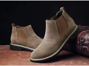 Detailansicht brauner Chelsea-Boots aus Wildleder mit Kontrastnähten auf dunklem Grund.