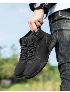 Vue détaillée des bottes Martin d'extérieur noires à tige haute tenues à la main dans la nature