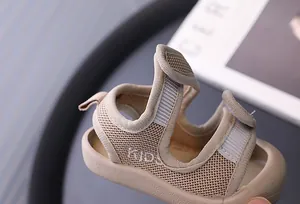 Close-up of breathable beige mesh baby sandals featuring protective closed toe and Velcro strap