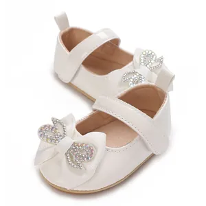 Close-up view of white baby girl princess shoes with a sparkling rhinestone bow