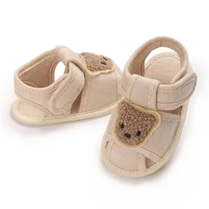 Vue détaillée de sandales bébé avec écusson ours pelucheux et bride velcro sûre
