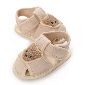 Gros plan de chaussures de marche pour bébé beiges avec une décoration d'ours en peluche.