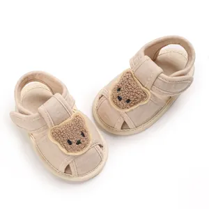 Détail de sandales de marche pour bébé en beige doux avec un joli patch d'ours en peluche