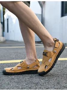 Gros plan latéral de sandales de plage en cuir marron cousues à la main pour hommes.