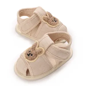 Chaussures de marche beiges pour bébé avec motif lapin en peluche et semelle souple.
