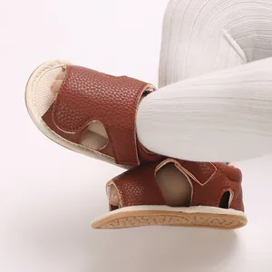 Close-up view of brown textured leather baby walking sandals with white ribbed stockings.