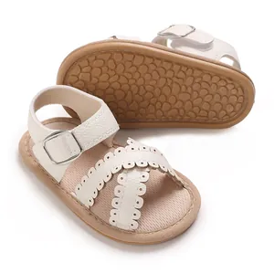 Detail van witte babysandalen met geschulpte kruisbandjes en een antislipzool met textuur.
