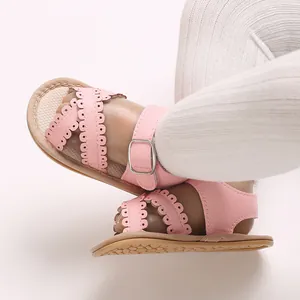 Detailopname van roze babysandalen met schulprandjes en een zilveren gespsluiting.