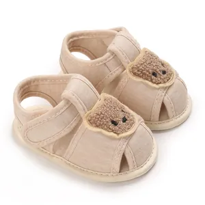 Détail des chaussures de marche pour bébé beiges avec un petit ours en peluche