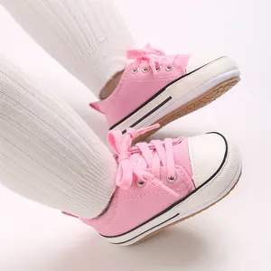 Close-up of pink baby canvas pre-walker shoes with soft soles worn with white leggings