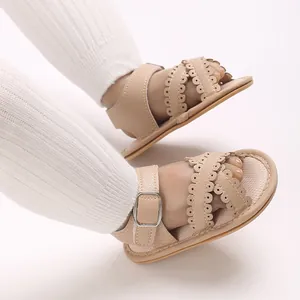 Detailopname van beige baby sandalen van leer met geschulpte bandjes en metalen gesp
