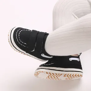 Vue détaillée de chaussures de marche pour bébé garçon en toile noire avec scratchs.