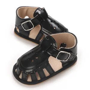 Close-up of black faux leather baby sandals with flower cut-outs and soft soles