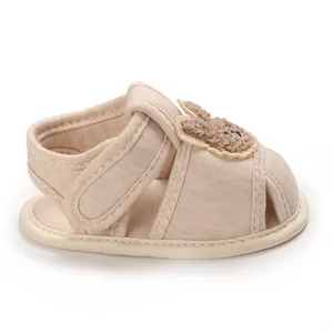 Détail latéral des chaussures de marche pour bébé avec motif ours et velcro.