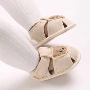 Gros plan de chaussures de marche pour bébé beige avec semelle souple et ours en peluche