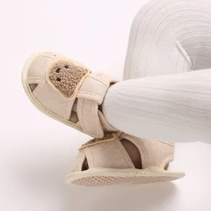 Gros plan de chaussures de marche pour bébé beiges avec motif d'ours et semelle souple