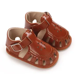 Macro view of brown synthetic leather baby girl sandals featuring elegant floral cutouts