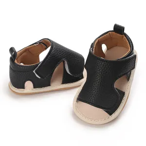 Detail van zwarte baby sandalen van generfd leer met zachte zool en klittenband