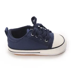 Side view of a navy blue baby canvas sneaker with white soft sole and toe cap.