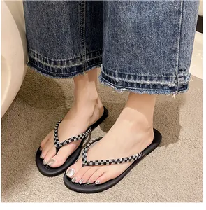 Gros plan de tongs noires pour femmes avec lanières à carreaux et strass aux pieds