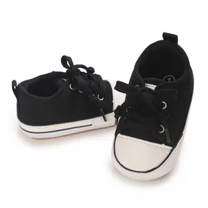Close-up of black and white baby canvas sneakers with soft soles and laces
