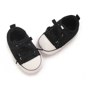 Close-up detail of classic black and white canvas baby sneakers for pre-walking infants