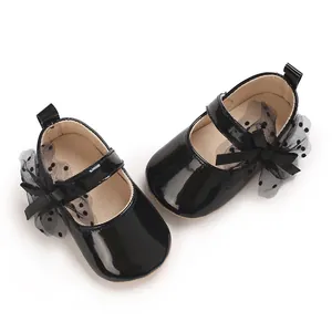 Nahaufnahme schwarzer Lackleder-Lauflernschuhe für Babys mit dekorativen Spitzen-Schleifen.