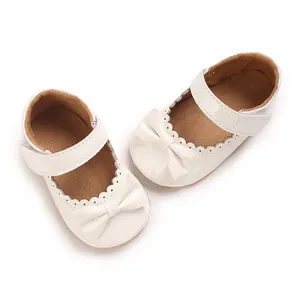 Vista detallada de zapatos de bebé en PU blanco con bordes ondulados y un lazo