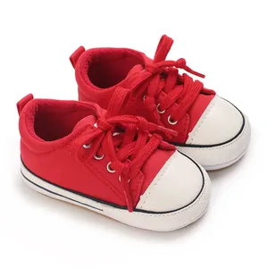 Detailed view of red canvas infant sneakers with soft soles and white toe caps.