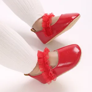 Détail de chaussures de princesse en cuir verni rouge pour bébé avec bordure à volants