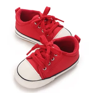 Detail of red baby canvas shoes with soft soles and white toe caps for infants