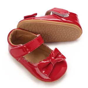 Vista detallada de zapatos de princesa para bebé en charol rojo con un lazo elegante