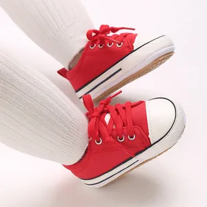 Close-up of red infant canvas pre-walking shoes with soft soles and white socks.