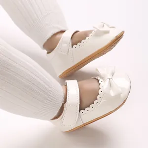 Primer plano de zapatos de princesa para bebé en cuero PU blanco con lazo y ondas.