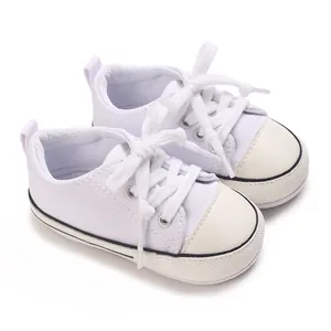 Side view detail of white baby canvas sneakers with soft soles for pre-walking infants