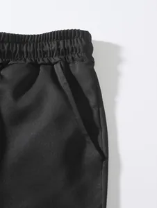 Detail showing elastic waistband and side pocket of black woven men's shorts