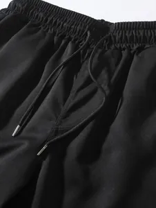 Detail of men's woven shorts showing elastic waistband and drawstring with metal tips.