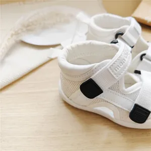 Detailed macro view of white breathable mesh baby walking sandals with secure velcro strap