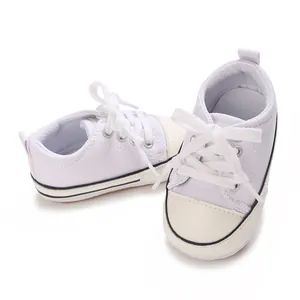 Detailed view of white canvas baby pre-walker sneakers featuring soft soles and cotton laces
